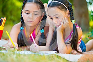 Hispanic sisters drawing in summer park