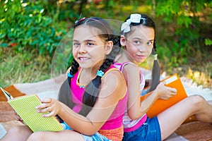 Hispanic sisters reading in summer park