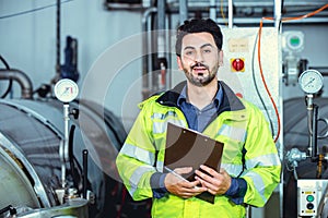 Hispanic smart confident engineer male service worker in factory portrait in boiler water pipe room