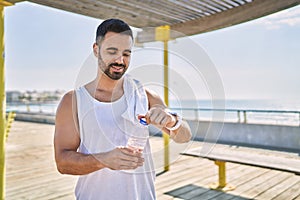 Hispanic sports man wearing workout style drinking water to stay hydrated outdoors on a sunny day