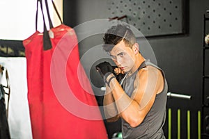 Hispanic sporty man punching a boxing bag