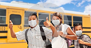 Three Hispanic Students Near School Bus Wearing Face Masks photo