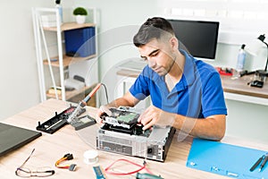 Hispanic technician installing a hard drive on a CPU