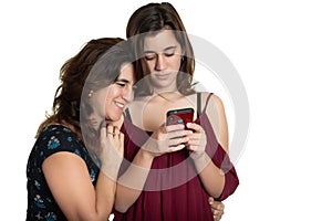 Hispanic teenage girl and her affectionate mother looking at a smartphone