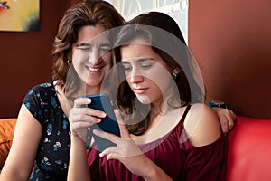 Hispanic teenage girl and her mother looking at a smartphone