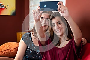 Hispanic teenage girl and her mother taking a selfie at home