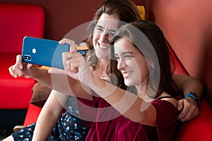 Hispanic teenage girl and her mother taking a selfie at home