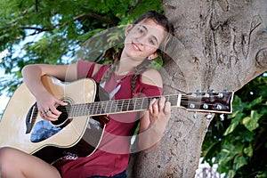 Hispanic teenage girl playing an acoustic guitar