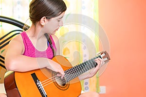 Hispanic teenage girl playing guitar at home