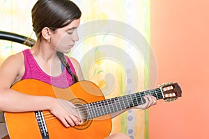 Hispanic teenage girl playing guitar at home