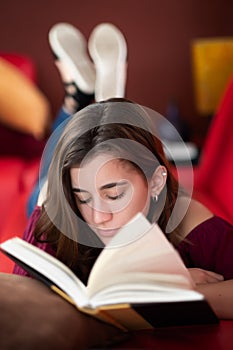 Hispanic teenage girl reading a book at home