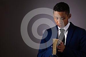 Hispanic Teenager Boy Seeking to Commune with God Via Prayer and Holding the Holy Bible photo