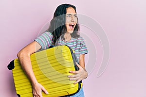 Hispanic teenager girl with dental braces holding cabin bag angry and mad screaming frustrated and furious, shouting with anger