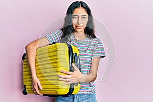 Hispanic teenager girl with dental braces holding cabin bag skeptic and nervous, frowning upset because of problem