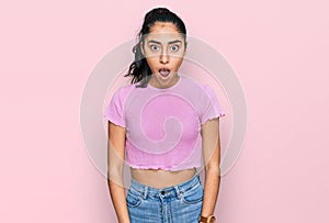 Hispanic teenager girl with dental braces wearing casual clothes afraid and shocked with surprise and amazed expression, fear and