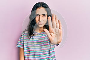 Hispanic teenager girl with dental braces wearing casual clothes doing stop sing with palm of the hand