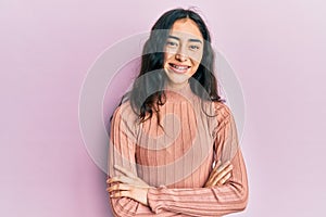 Hispanic teenager girl with dental braces wearing casual clothes happy face smiling with crossed arms looking at the camera