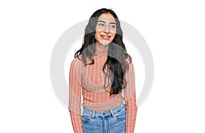 Hispanic teenager girl with dental braces wearing casual clothes looking away to side with smile on face, natural expression
