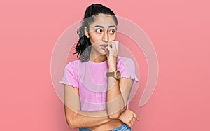 Hispanic teenager girl with dental braces wearing casual clothes looking stressed and nervous with hands on mouth biting nails