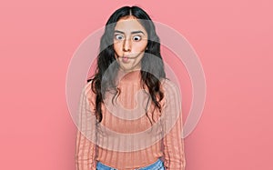 Hispanic teenager girl with dental braces wearing casual clothes making fish face with lips, crazy and comical gesture