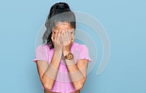 Hispanic teenager girl with dental braces wearing casual clothes with sad expression covering face with hands while crying