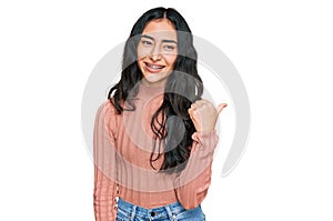 Hispanic teenager girl with dental braces wearing casual clothes smiling with happy face looking and pointing to the side with