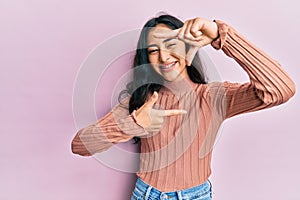 Hispanic teenager girl with dental braces wearing casual clothes smiling making frame with hands and fingers with happy face