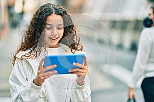 Hispanic teenager girl smiling happy using touchpad at the city