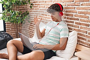 Hispanic teenager using laptop at home sitting on the bedroom celebrating victory with happy smile and winner expression with