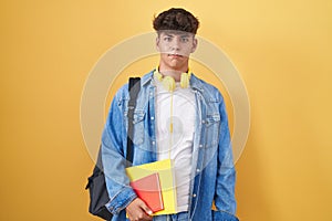 Hispanic teenager wearing student backpack and holding books depressed and worry for distress, crying angry and afraid