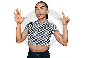 Hispanic transgender man wearing make up and long hair wearing modern clothes showing and pointing up with fingers number seven