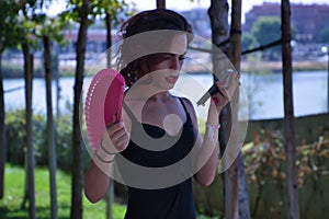 Hispanic and transsexual young adult girl smoking, with a pink fan and talking on the handsfree phone. Concept of transsexuality,
