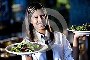 Hispano camarera en un restaurante porciones ensaladas 