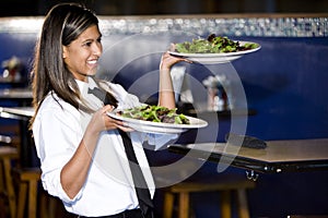 Hispanic waitress serving salads photo