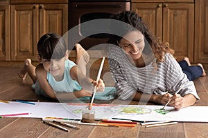 Hispanic woman babysitter engaged in drawing picture with little girl