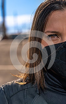 Hispanic woman with brown eyes wearing a mask and posing with a serious face expression