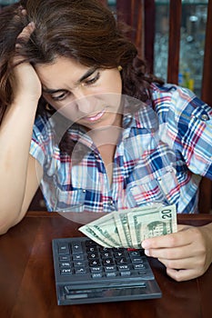 Hispanic woman counting money at home to pay the bills