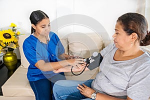 Hispanic woman doctor uses blood pressure check and consults woman patient