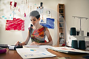 Hispanic woman doing budget in fashion atelier