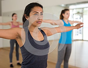 Hispanic woman doing warmup during group workout at gym