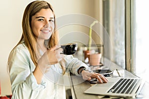 Hispanic woman drinking coffee and working