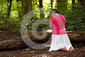 Woman in Forest Preserve with Bible Kneeling in Prayer photo