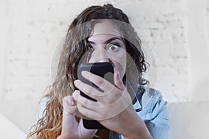 Hispanic woman holding mobile phone in crazy eyes social network and internet addiction concept