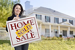 Hispanic Woman Holding Sold Home Sale Sign in Front of House