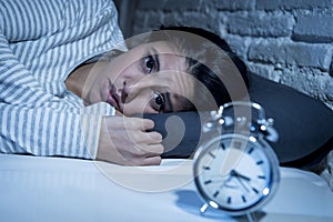 Hispanic woman at home bedroom lying in bed late at night trying to sleep suffering insomnia