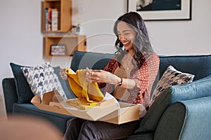 Hispanic woman opening parcel package from online shop