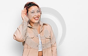 Hispanic woman with pink hair wearing casual clothes smiling with hand over ear listening an hearing to rumor or gossip