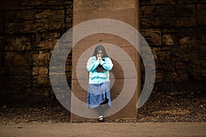 Hispanic Woman Prays By Wall photo