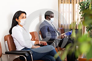 Hispanic woman in protective mask waiting for job interview in office