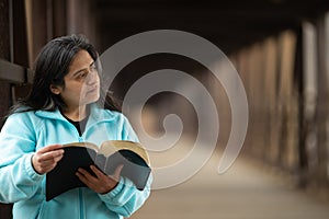 Hispanic Woman Reading Bible On Bridge